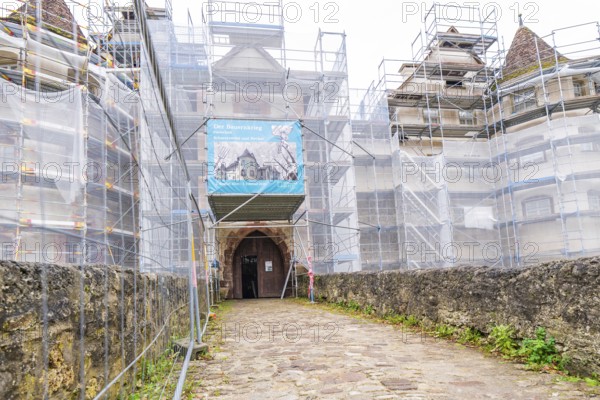 Entrance gate of a medieval building with scaffolding, surrounded by an old sandstone wall, Glatt moated castle, Sulz, Germany