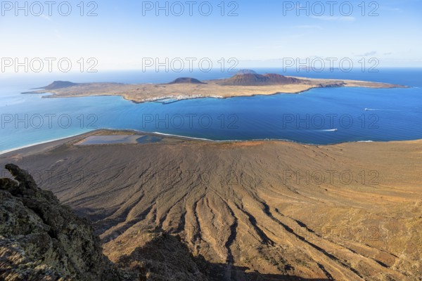 View of steep cliffs by the sea and island of La Graciosa with volcanic craters in the evening light, Mirador del RÃ­o viewpoint designed by artist CÃ©sar Manrique, Lanzarote, Canary Islands, Spain