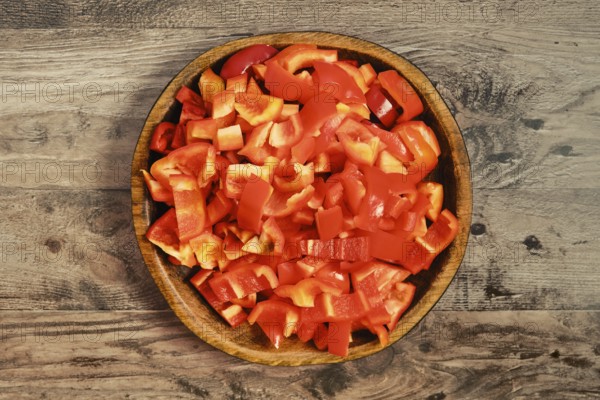 Freshly chopped red bell peppers in a wooden bowl. The chopped pieces are neatly arranged, ready to be used in various dishes