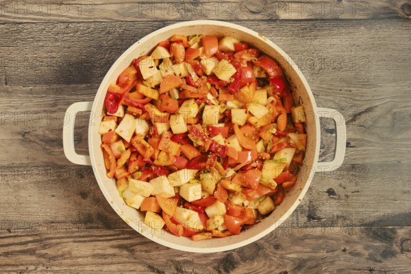 Chopped bell peppers, tomatoes, and onions are mixed together in a large pot, showcasing fresh ingredients being cooked. The vibrant colors are appealing and suggest a nutritious meal is underway