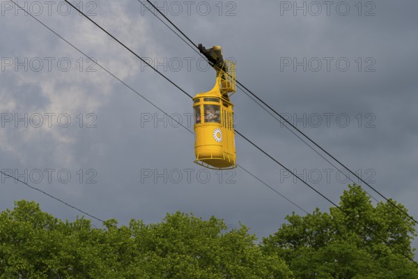 Yellow cable car floating over green trees under cloudy sky, cable car cabin, Kutaisi, Imereti region, Georgia