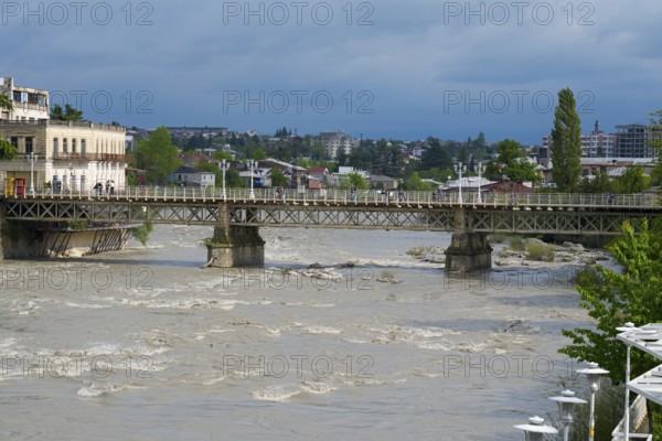 A rustic bridge across a river with an urban backdrop under cloudy sky, White Bridge over the Rioni River, Kutaisi, Imereti Region, Georgia
