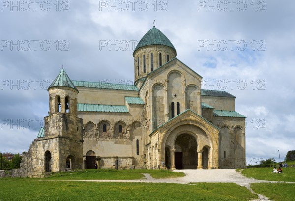 An impressive cathedral with green domes under a cloudy sky in a meadow, Bagrati Cathedral, Church of the Dormition of the Most Holy Mother of God, UNESCO World Heritage Site, Kutaisi, Imereti Region, Georgia