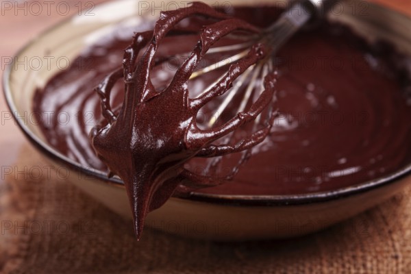A bowl of chocolate dough, a whisk for whipping, baking, structure and consistency, homemade, top view, no people