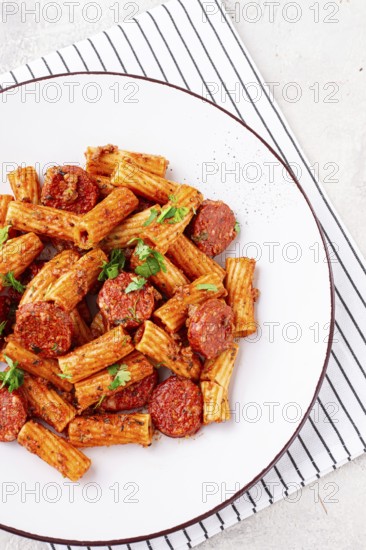 Rigatoni pasta with spicy sausage, and rich tomato sauce served, on a white plate, homemade