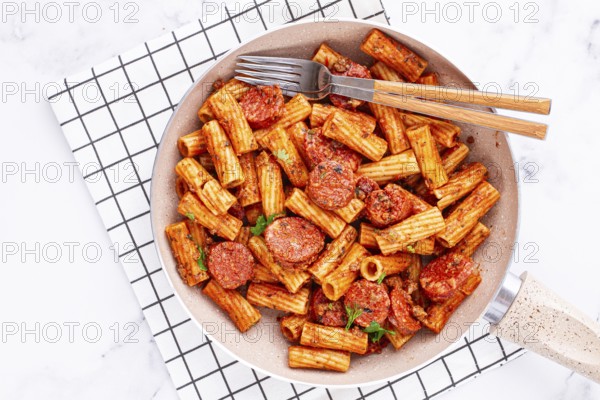 Rigatoni pasta with spicy sausage, and rich tomato sauce served, on a white plate, homemade
