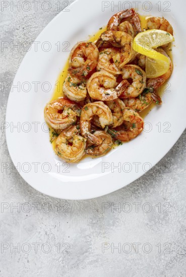 Fried tiger prawns, jumbo, in garlic sauce, in butter, with herbs, on a white plate, homemade, no people