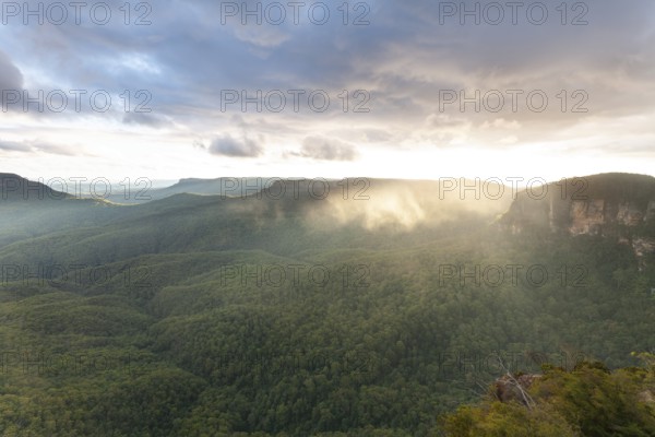 Evening sky with clouds of fog and setting sun at the Three Sisters at Echo Point in Katoomba, Blue Mountains, New South Wales, Australia
