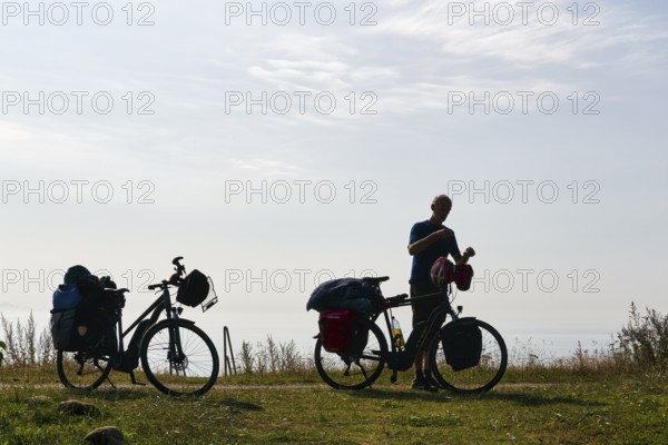Two e-bikes with luggage bags, cyclist taking a break, back light, Ystad, Sweden