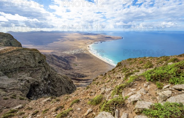 View from the Risco de Famara cliffs to the coast and the sea with the Famara beach, Playa de Famara with La Calaeta, Lanzarote, Canary Islands, Spain