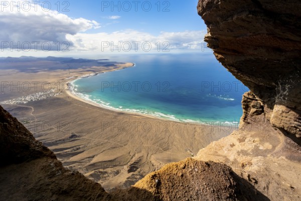 Cueva de las Cabras cave, view from the Risco de Famara cliffs on Famara beach, Playa de Famara with La Calaeta, Lanzarote, Canary Islands, Spain
