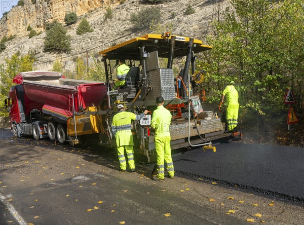 Asphalt road construction team of workers resurfacing tarmac in rural area, near Albarracin, Teruel province, Aragon, Spain