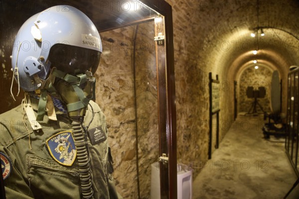 A helmet and pilot's suit behind glass in an illuminated tunnel, War Museum, Military Museum, Tunnel Museum, Lakki, Leros, Dodecanese, Greek Islands, Greece