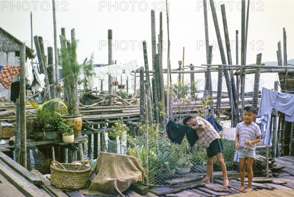 Children in fishing village on stilts with attap houses of Singapore, southeast Asia 1963