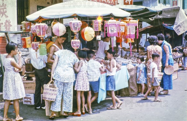 People at busy street market stall in Singapore, southeast Asia, c 1964
