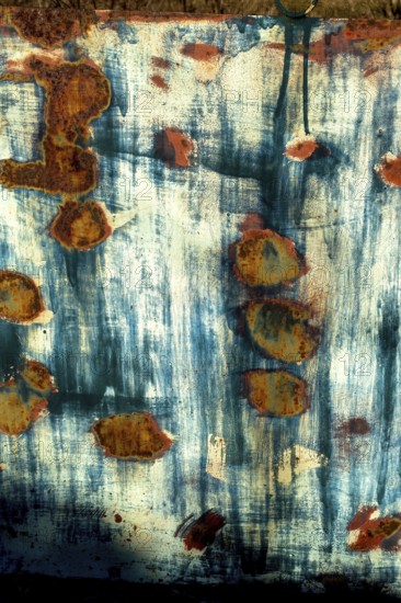 Textured surface revealing rust patterns on a weathered metal sheet in an outdoor setting during daylight