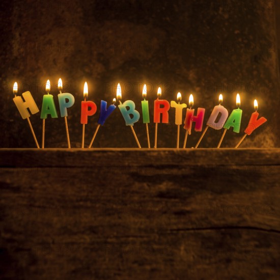 Brightly lit birthday candle arrangement spelling out Happy Birthday on a rustic wooden surface for a joyful celebration moment