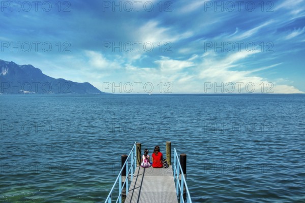 Switzerland. Mother and daughter sitting on a pontoon on the shores of Lake Geneva in Montreux