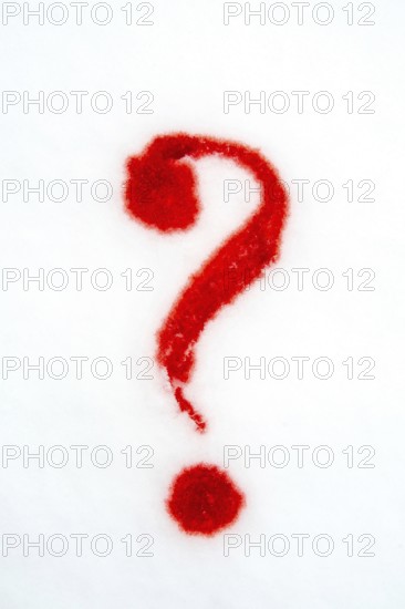 A vibrant red question mark is formed on a plain white surface using red powder, enhancing visual interest and prompting curiosity