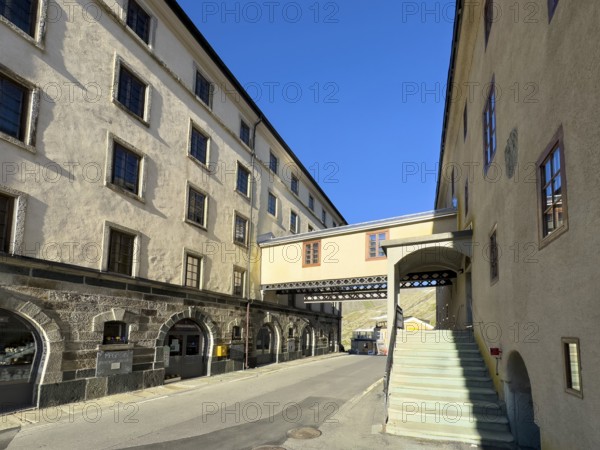 On the left, Swiss hotel hostel Auberge de Grand Gd. St. Saint Bernard on the right, historic hospice with accommodation at the top of the Alpine pass Grenzpass Großer Sankt Bernhard Pass, in between bridge with connecting passage over pass road from Col du Grand-Saint-Bernard Colle del Gran San Bernardo, Canton Valais, Switzerland