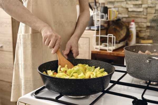 Cooking chopped bell peppers in a modern kitchen with natural light streaming through the window