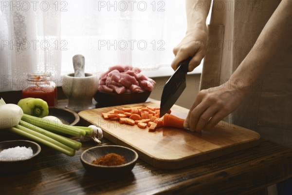 In a warm kitchen, a person skillfully chops fresh carrots on a wooden cutting board