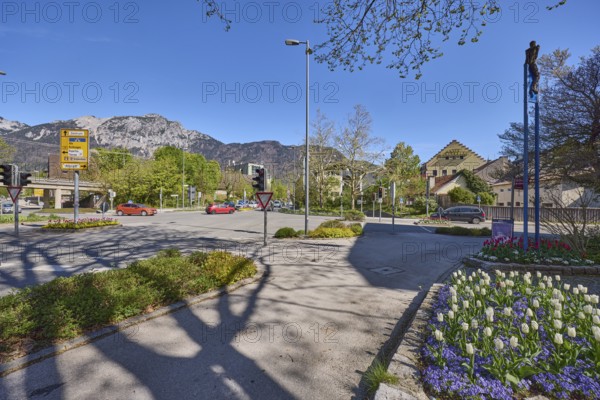 Streets, traffic lights, lantern, trees, flower bed, tulips (Tulipa), general architecture, mountain landscape, mountains, shadow, blue sky, cirrostratus clouds, federal highway 20, intersection between Anton-Winkler-Straße, Innsbrucker Straße, Kammerbotenstraße and Reichenbachstraße, Bad Reichenhall, district Berchtesgadener Land, Bavaria, Germany
