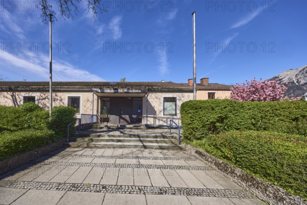 St. Nikolaus parish hall, flagpoles, hedge, stairs, paving slabs, cobblestones, blue sky, cirrostratus clouds, Bundesstraße 20, Anton-Winkler-Straße, Bad Reichenhall, Berchtesgadener Land district, Bavaria, Germany