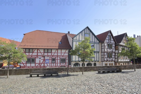 Colourful half-timbered houses, red, green, brown, empty benches, churchyard, Schmalkalden, Franconia, Thuringia, Germany