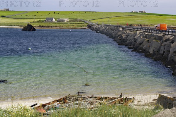 Ruin of a boat on the beach with a breakwater and green coastal background, Churchill Bariers, Lambholm, Scapa Flow, Orkney Islands, Scotland, United Kingdom