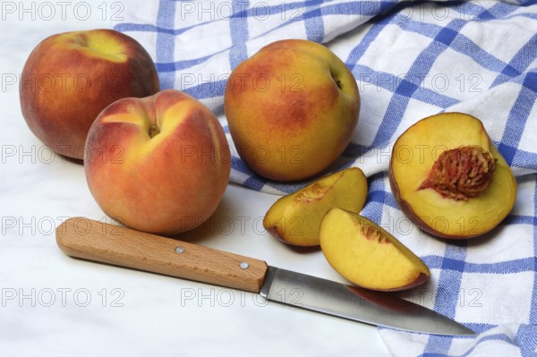 Peach with knife on kitchen towel, peach halves, Prunus persica