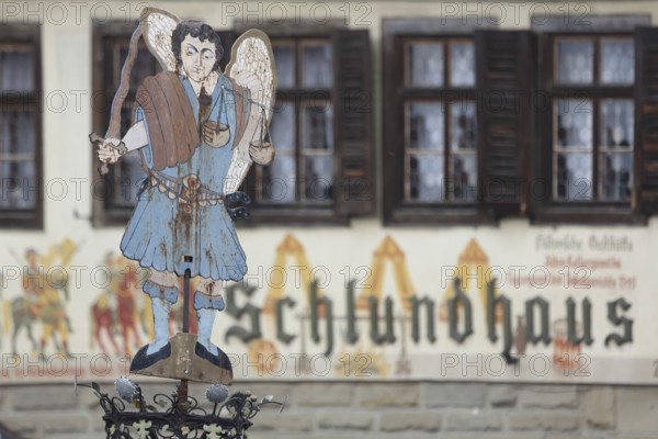 Figure at the Luitpold fountain built in 1911, fountain, angel, sword, stabbing weapon, beam balance, symbol, Justitia, sheet metal, metal, hotel, Schlundhaus, inscription, depth of field, blur, market square, Bad Königshofen, Rhön, Lower Franconia, Franconia, Bavaria, Germany