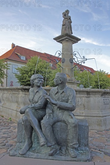 Market fountain with bronze sculpture, modern art, male figure, female figure, couple, sitting, conversation, entertainment, talking, listening, looking, joy, joyful, friends, relationship, communication, friendship, partnership, Schleusingen, Thuringia, Germany