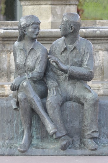 Bronze sculpture at the market fountain, modern art, male figure, female figure, couple, sitting, conversation, entertainment, talking, listening, looking, joy, joyful, friends, relationship, communication, friendship, partnership, Schleusingen, Thuringia, Germany