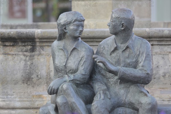Bronze sculpture at the market fountain, modern art, male figure, female figure, couple, sitting, conversation, entertainment, talking, listening, looking, joy, joyful, friends, relationship, communication, friendship, partnership, Schleusingen, Thuringia, Germany