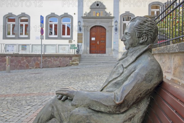 Johann Wolfgang von Goethe by Klaus Gutting sitting on the bench, arms, bronze sculpture, looking, monument, modern art, GoetheStadtMuseum, Amtshaus, town hall, door, market place, Ilmenau, Thuringian Forest, Thuringia, Germany