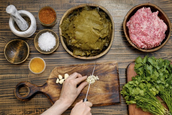 Preparing dolma at home involves chopping garlic and herbs while surrounded by fresh grape leaves and seasoned meat. The rich aromas create a delightful cooking atmosphere in the kitchen
