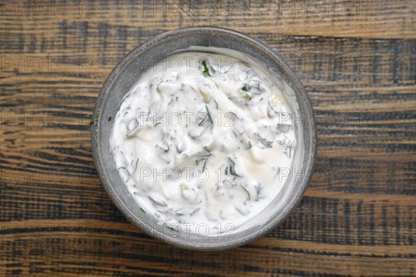 Overhead view of a bowl with sour cream mixed with chopped parsley, cilantro and garlik. Classic dipping sauce