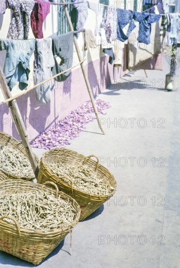 Clothes handing out to dry with baskets of what is thought to be clothes pegs, clothespins, Macau, Asia 1964