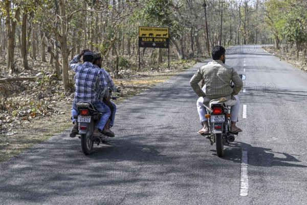 Motorcyclist in front of a Wildlife Corridor sign, Corbett National Park, near Ramnagar, Uttarakhand State, India