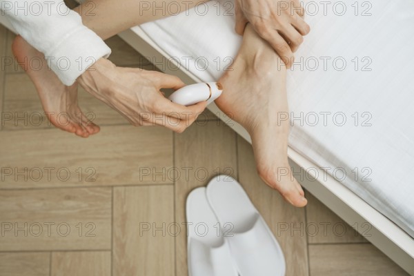 Close-up overhead view of peeling dead skin off foot with electric exfoliating machine