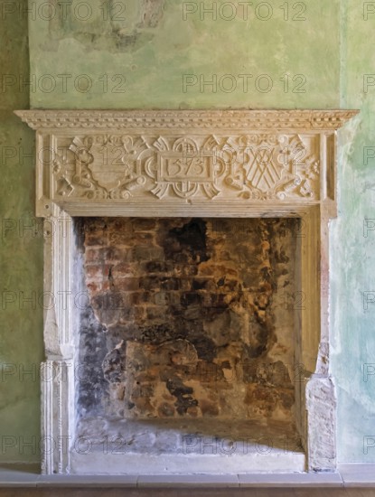 Artfully carved stone fireplace in green antique surroundings with exposed bricks, Lüdinghausen Castle, Lüdinghausen, Münsterland, North Rhine-Westphalia, Germany