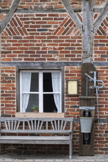 Half-timbered house, half-timbered façade with bench and swing pump, Borken-Gemen Heritage House, Münsterland, North Rhine-Westphalia, Germany