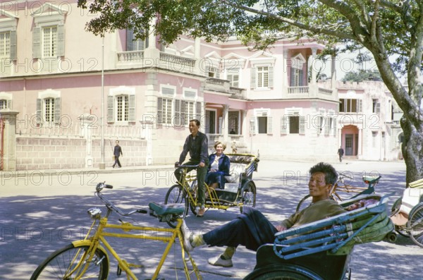 Tricycle rickshaw rider outside Governor's Palace, Portuguese colonial villa building, Avenida da Praia Grande, Macau, Asia 1964