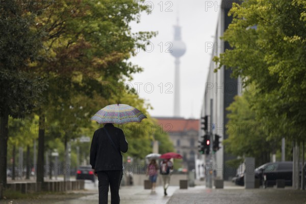 People walk with umbrellas through the government district in Berlin, 21.07.2025