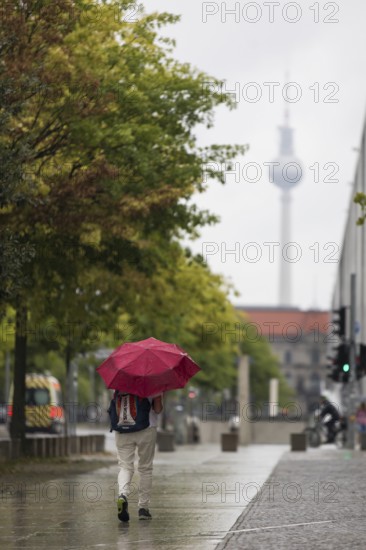 People walk with umbrellas through the government district in Berlin, 21.07.2025