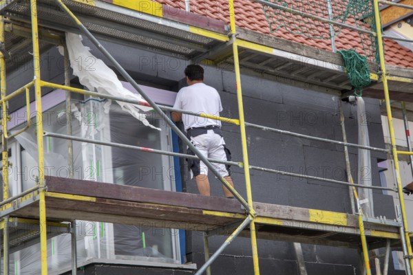 Construction workers insulate a house facade