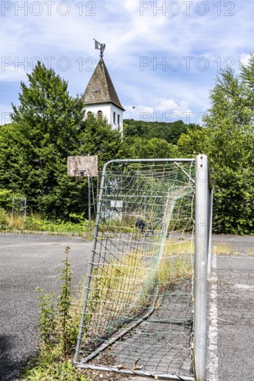 Old sports field, with asphalt floor, weeds reclaiming the field, apparently abandoned football pitch in Schmallenberg-Dorlar, in the Hochsauerland district, North Rhine-Westphalia, Germany