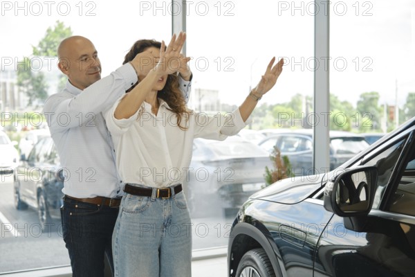 Husband gives his wife a new car while covering her eyes at a dealership