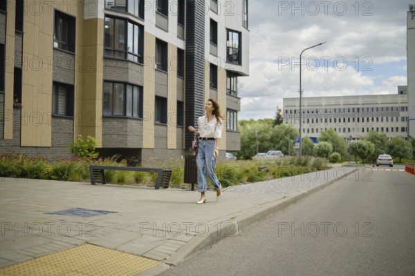 Woman strolling along the street in urban area with modern architecture on a cloudy afternoon